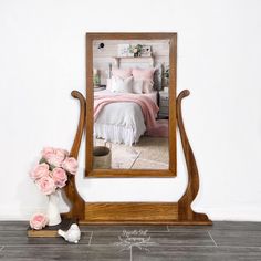 a mirror sitting on top of a wooden stand next to a vase with flowers in it