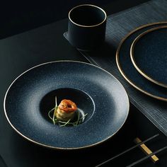 a black plate with some food on top of it next to a cup and saucer