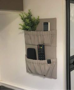 there is a cell phone and remote control in the pocket of this wall hanging organizer