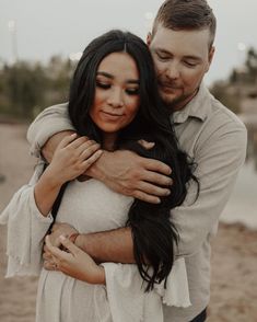 a man and woman hugging each other on the beach