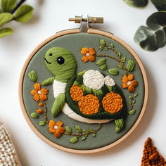 a close up of a embroidery on a hoop with flowers and a turtle in the center