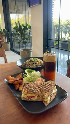 there is a sandwich and salad on the plate next to a glass of beer in front of it