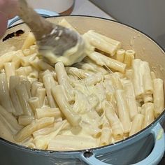 someone is stirring pasta into a pot on the stove