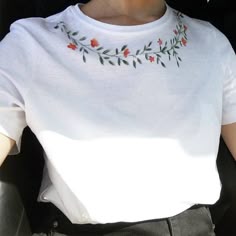 a woman wearing a white shirt with red flowers on it