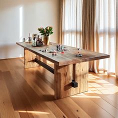 a wooden table sitting on top of a hard wood floor next to a vase with flowers