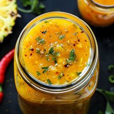 two jars filled with food sitting on top of a black table next to red peppers