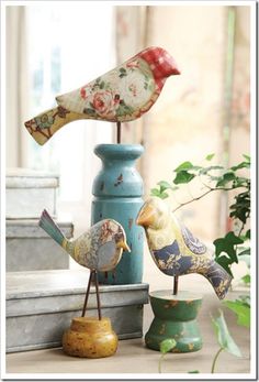 two birds sitting on top of a blue vase next to another bird figurine