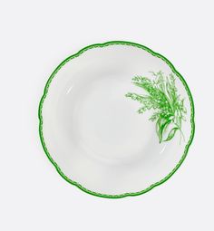 a green and white plate with some flowers on it's rim, against a white background