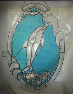 a stained glass window with a dolphin on it's side and bubbles in the water