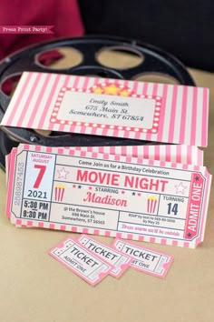 two pink and white movie tickets sitting on top of a table next to a pair of glasses