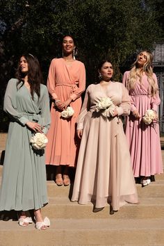 four women in long dresses standing on steps