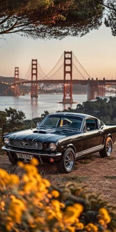 an old mustang parked in front of the golden gate bridge