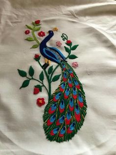 embroidered peacock on white fabric with red flowers