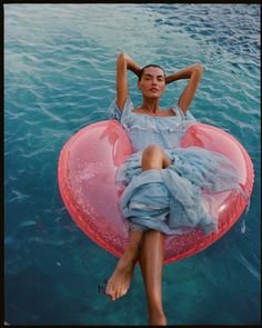 a woman laying on top of an inflatable object floating in the ocean water