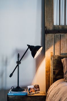 a bed with a lamp on top of it next to a book and some pictures