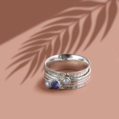 Experience the ancient Holi ethos of purification with this silver meditation ring. The Holi Tranquility spinner ring allows you to manifest peace and serenity with a single spin. Sustainably-sourced pearl and tanzanite gemstones adorn this handmade silver spinning ring; the perfect gift for anyone with June or December birthdays.   Sterling Silver, Tanzanite (0. 4cm), Pearl (0. 3cm)  All of our stones are real so colours may vary Handmade Handmade jewellery made from sterling silver, brass, bro Manifest Peace, Charlotte's Web, Spinning Ring, Meditation Ring, Spinning Rings, June Birthstone Jewelry, Spinner Ring, Jewelry Ring Box, Handmade Rings