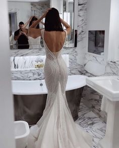 a woman standing in front of a bath tub wearing a dress with beading on it