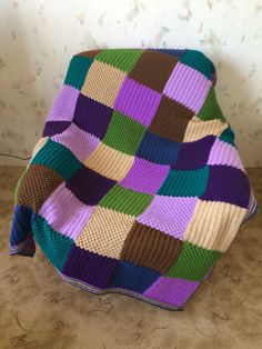 a multicolored blanket sitting on the floor next to a wall with flowers in it