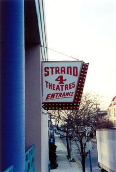 the sign is hanging from the building on the side of the street that says strand 4 theatre entrance