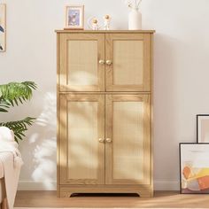 a wooden cabinet with wicker doors in a white living room next to a plant