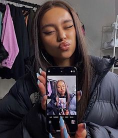 a woman taking a selfie with her cell phone in front of her ear and nose