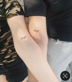 two people with matching tattoos on their arms, one is holding the other's arm