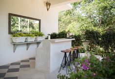 an outdoor bar with stools and potted plants on the counter in front of it