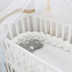 a white crib with a black pillow in the middle and stars on the bottom