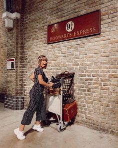 a woman standing next to a cart full of luggage in front of a hogwarts express sign