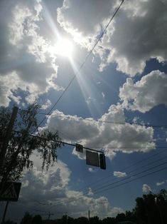 the sun shines brightly through the clouds above power lines and street signs on a cloudy day