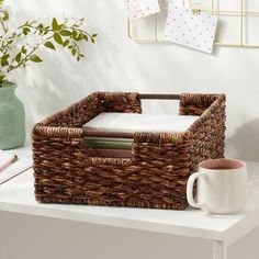 a wicker basket sitting on top of a table next to a cup and pen