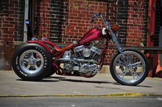 a red and black motorcycle parked on the side of a road next to a brick building