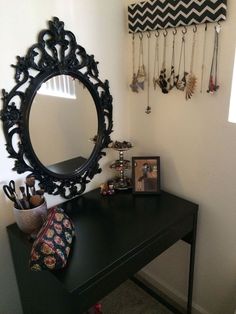 a black table with a mirror and jewelry hanging on the wall next to an empty shelf