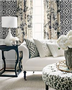 a living room with black and white wallpaper on the walls, furniture and flowers