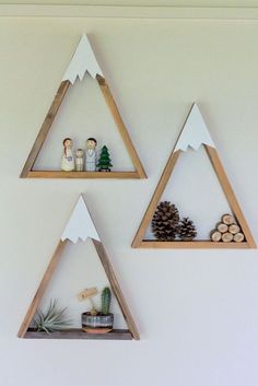 three wooden triangle shelves with pine cones and decorations on them, hanging from the wall