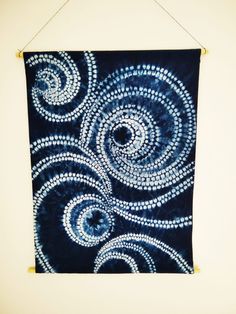 a blue and white wall hanging with an artistic design on it's back side