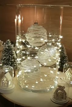 a table topped with lots of glass bowls filled with snow globes and christmas lights