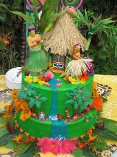 a green cake decorated with flowers and tiki figures