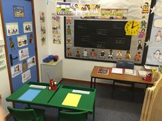 a classroom with green tables and chairs in front of a chalkboard that says welcome to children's day