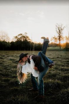 a man and woman kissing in the middle of a field