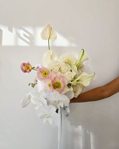 a woman holding a bouquet of flowers in her hand with white and pink flowers on it