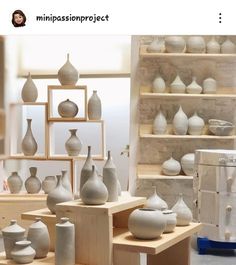 many white vases are on display in a room