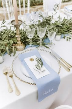 the table is set with silverware and greenery for an elegant touch to the place setting