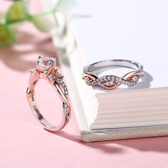 two wedding rings sitting on top of a book next to flowers and a flower vase