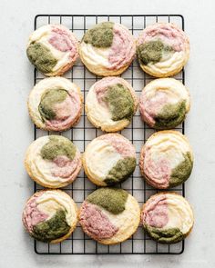 a cooling rack filled with cookies covered in green and pink icing