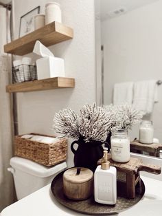 a bathroom with a white toilet and wooden tray on the sink counter next to it