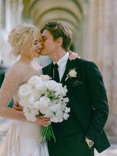 a bride and groom kissing in front of a building