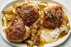 two meatballs with onions and sauce on a white plate, ready to be eaten