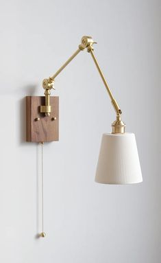 a wall light with a white shade hanging from it's side on the wall