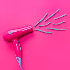 a pink blow dryer sitting on top of a pink table next to blue and white toothbrushes